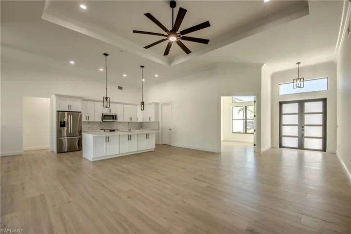 Kitchen featuring appliances with stainless steel finishes, a tray ceiling, decorative light fixtures, and white cabinets