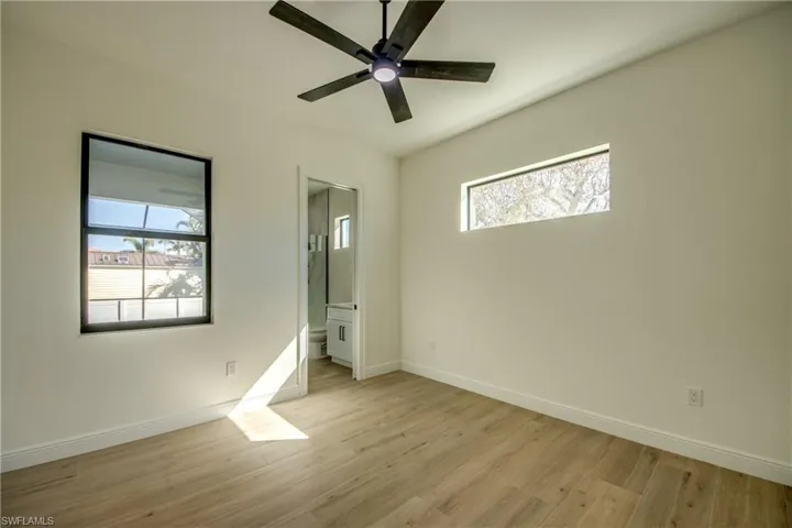 Unfurnished bedroom with connected bathroom, light wood-type flooring, and ceiling fan