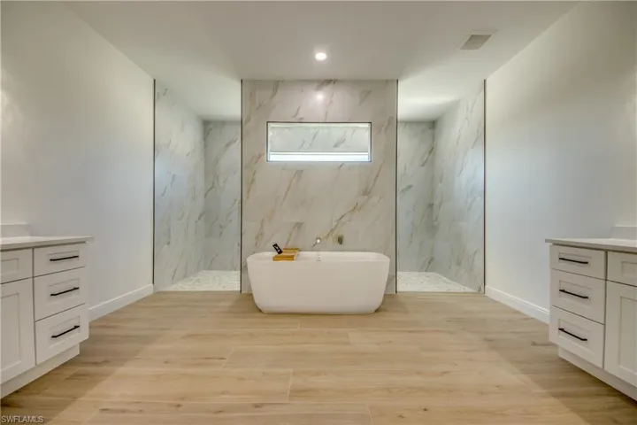 Bathroom featuring wood-type flooring, vanity, and separate shower and tub