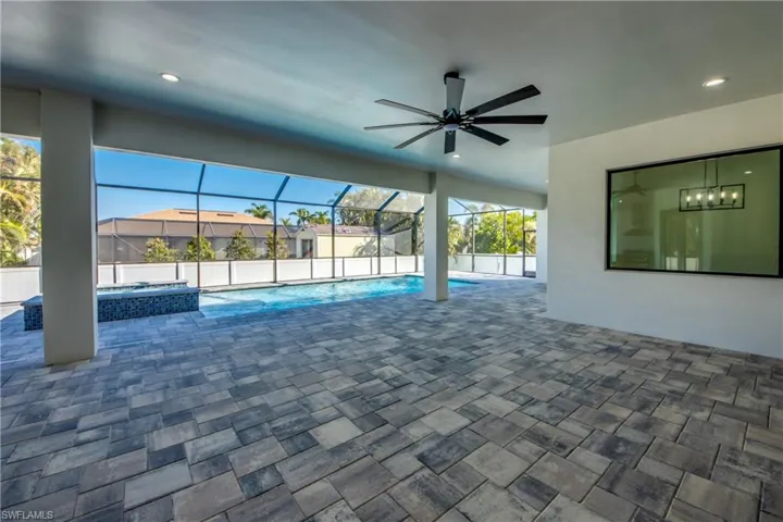 View of swimming pool with an in ground hot tub, ceiling fan, a patio area, and a lanai