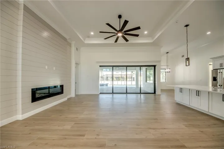 Unfurnished living room with a fireplace, ceiling fan, a raised ceiling, and light hardwood / wood-style flooring
