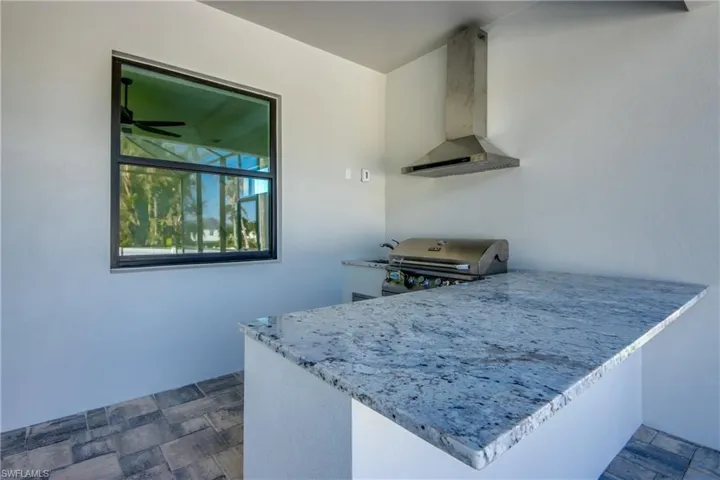 Kitchen featuring kitchen peninsula, wall chimney exhaust hood, and ceiling fan