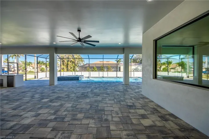 View of pool featuring ceiling fan, glass enclosure, and a patio area