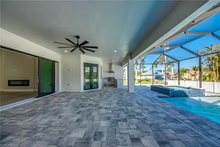 View of patio / terrace featuring a pool with hot tub, glass enclosure, and ceiling fan