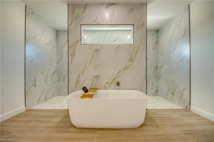 Bathroom with shower with separate bathtub, tile walls, and hardwood / wood-style flooring