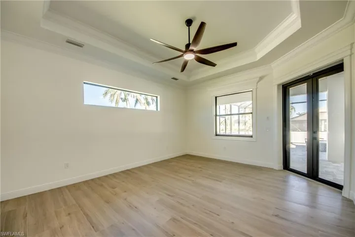 Spare room with crown molding, ceiling fan, light hardwood / wood-style floors, and a raised ceiling