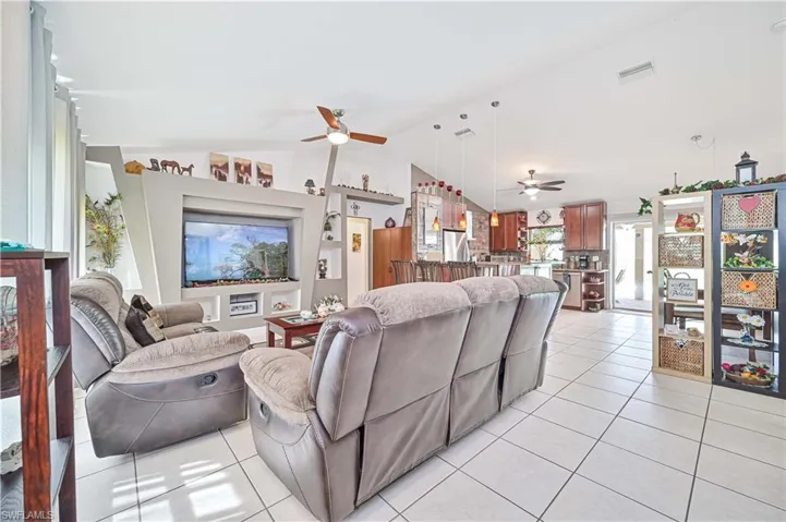 Living area featuring a ceiling fan, vaulted ceiling, and light tile patterned flooring