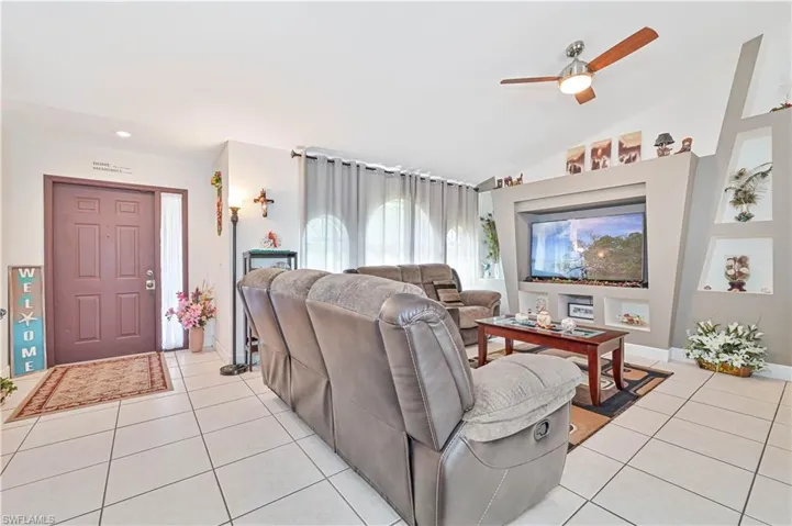 Living area with light tile patterned floors, a ceiling fan, vaulted ceiling, and recessed lighting