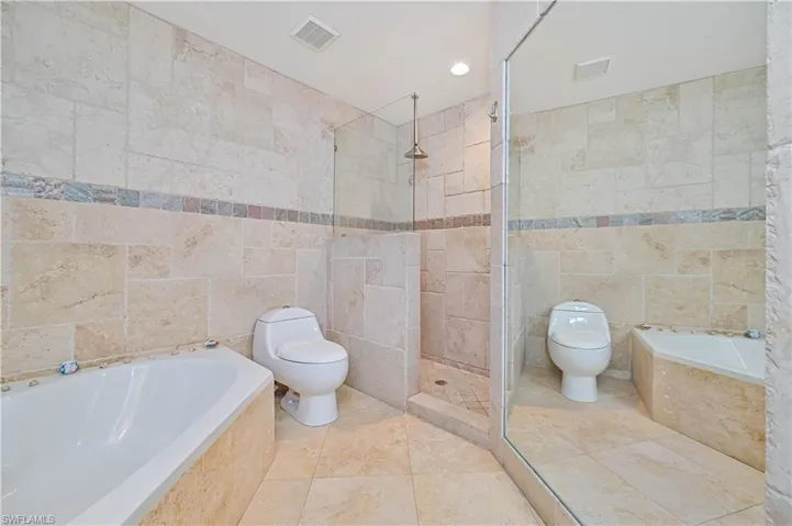 Full bathroom with tile walls, a garden tub, tiled shower, and recessed lighting