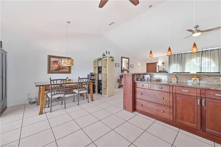 Dining space with ceiling fan, lofted ceiling, and light tile patterned flooring
