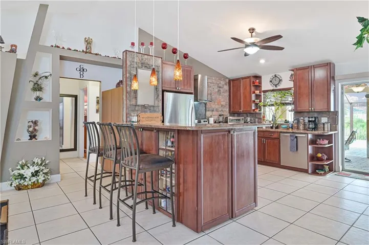 Kitchen featuring open shelves, stainless steel appliances, lofted ceiling, wall chimney range hood, and ceiling fan