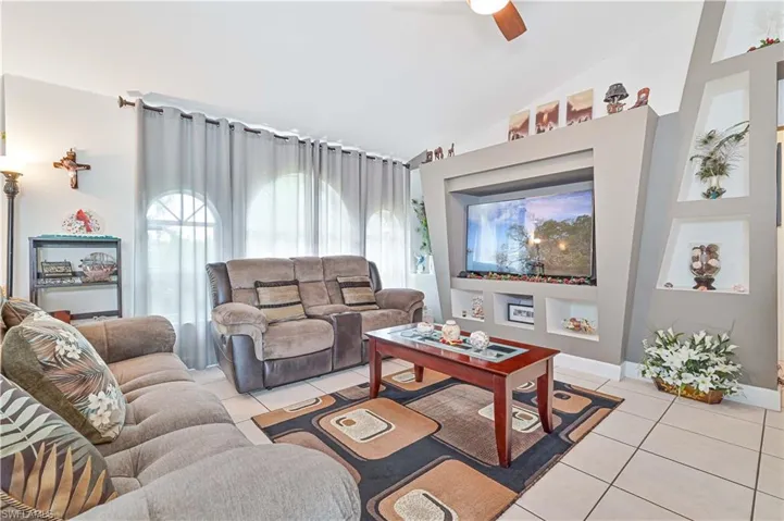Living area with light tile patterned floors, ceiling fan, and high vaulted ceiling