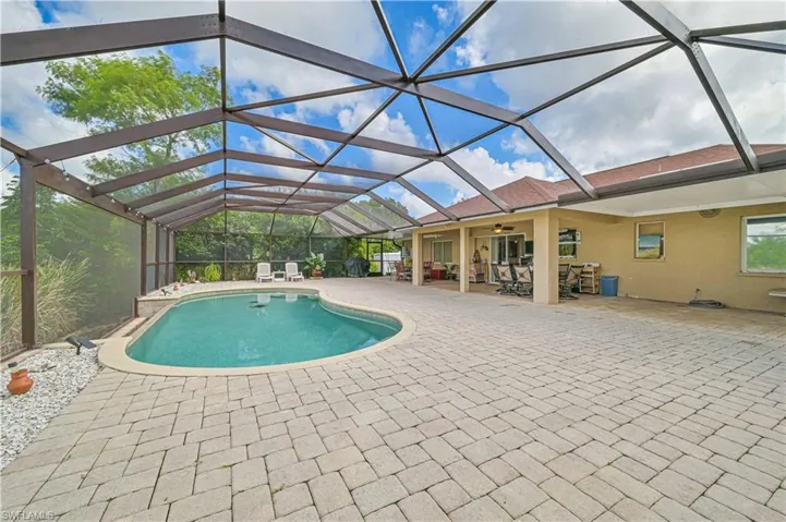 Outdoor pool featuring a patio, a ceiling fan, outdoor dining space, and a lanai