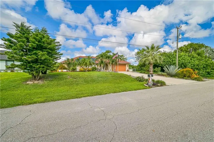 View of property hidden behind natural elements with driveway, a garage, and a front lawn