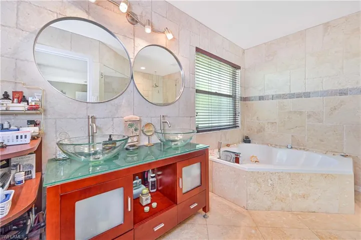 Bathroom featuring tile walls, a bath, tile patterned flooring, and double vanity