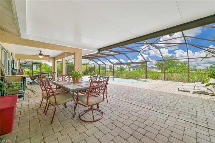 View of patio featuring an outdoor pool, outdoor dining area, a ceiling fan, and glass enclosure