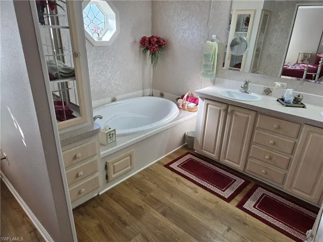 Bathroom featuring vanity, a bath, and hardwood / wood-style floors
