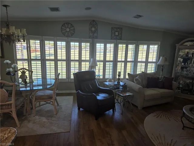 Living room with crown molding, dark hardwood / wood-style flooring, a chandelier, and vaulted ceiling