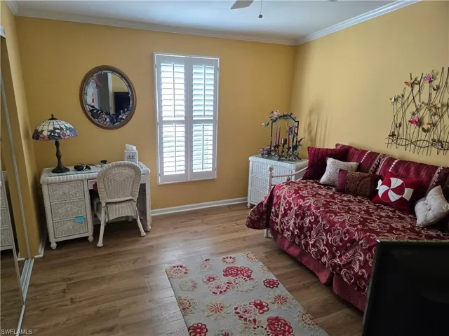 Bedroom featuring ornamental molding, wood-type flooring, and ceiling fan