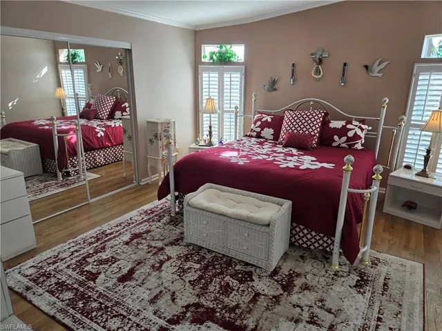 Bedroom with multiple windows, hardwood / wood-style floors, and ornamental molding