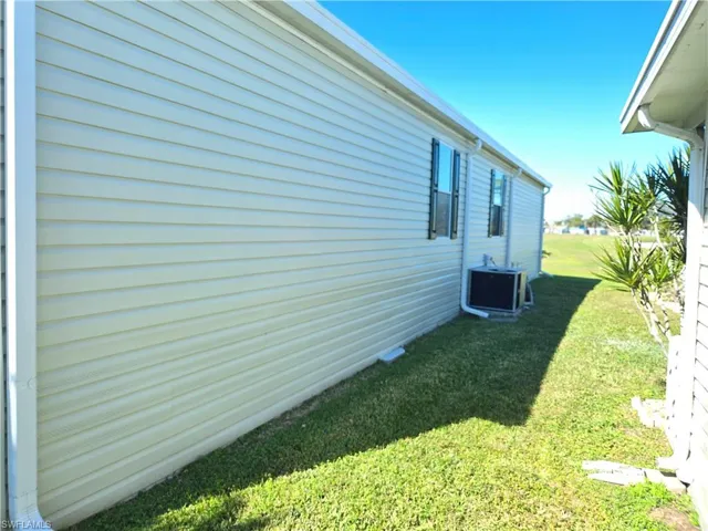 View of side of property with a lawn and central air condition unit