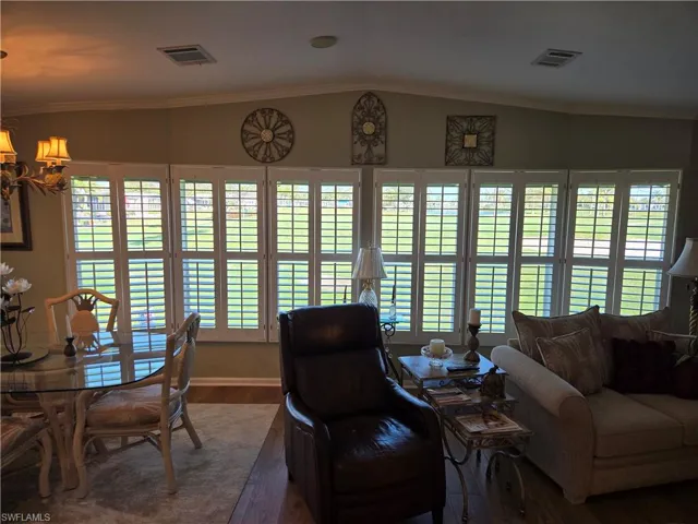 Living room with crown molding, plenty of natural light, and dark hardwood / wood-style flooring