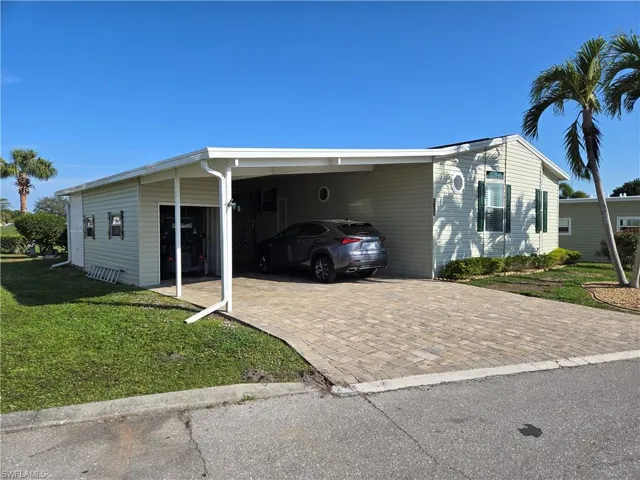 View of side of home featuring a carport and a lawn