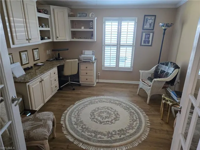 Office area featuring ornamental molding, built in desk, and hardwood / wood-style flooring
