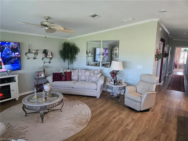Living room featuring hardwood / wood-style floors, ceiling fan, and ornamental molding
