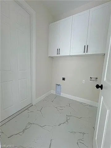 Washroom featuring light marble finish flooring, electric dryer hookup, cabinet space, and washer hookup