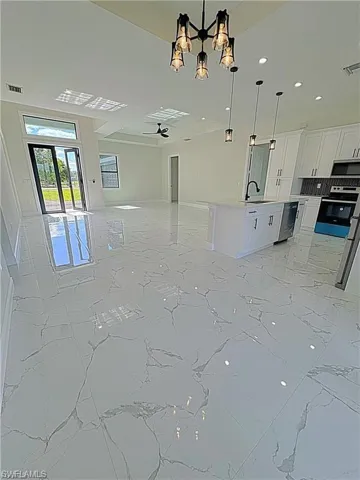 Unfurnished living room with light marble finish floors, a chandelier, ceiling fan, and recessed lighting