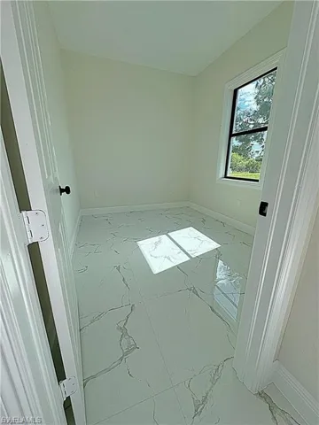 Unfurnished room with light marble finish flooring and baseboards