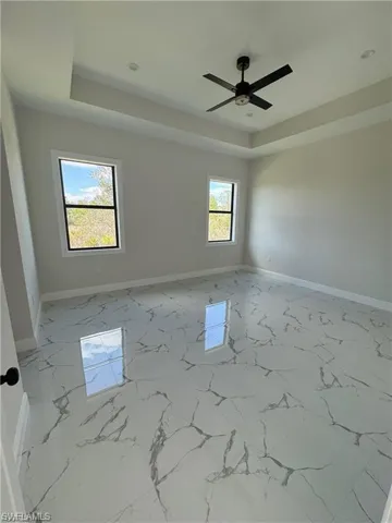 Empty room featuring a tray ceiling and light marble finish flooring