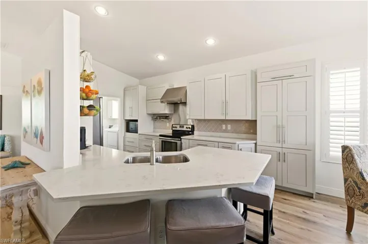 Kitchen with a breakfast bar, range with electric stovetop, tasteful backsplash