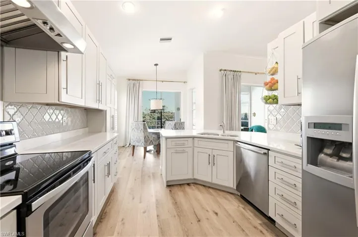 Kitchen featuring tasteful backsplash, appliances with stainless steel finishes, ventilation hood, a peninsula, and white cabinets