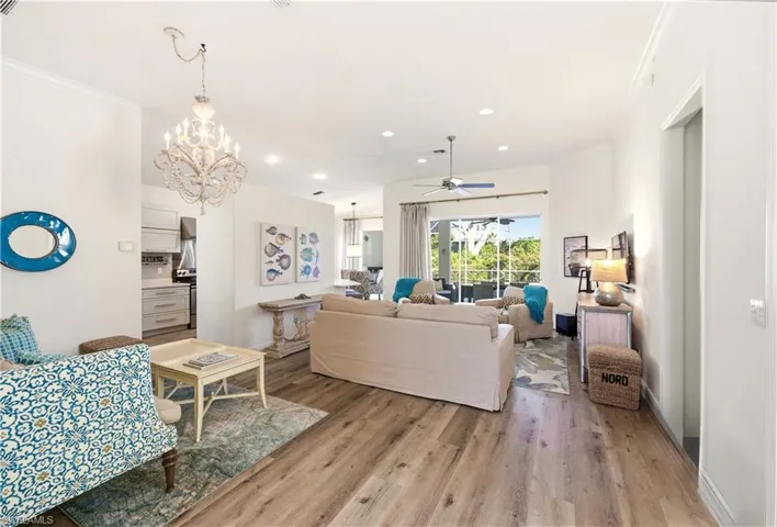 Living area featuring Luxury Vinyl flooring, a chandelier, recessed lighting, ceiling fan, and crown molding