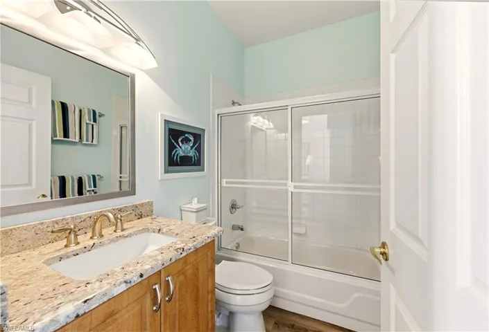 Guest Bathroom with shower / bath combination with glass door, vanity, and Luxury Vinyl floors