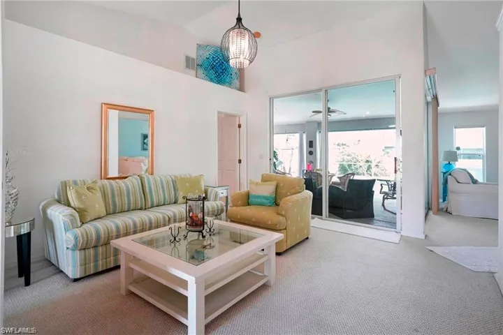 Living area featuring carpet floors, plenty of natural light, and vaulted ceiling