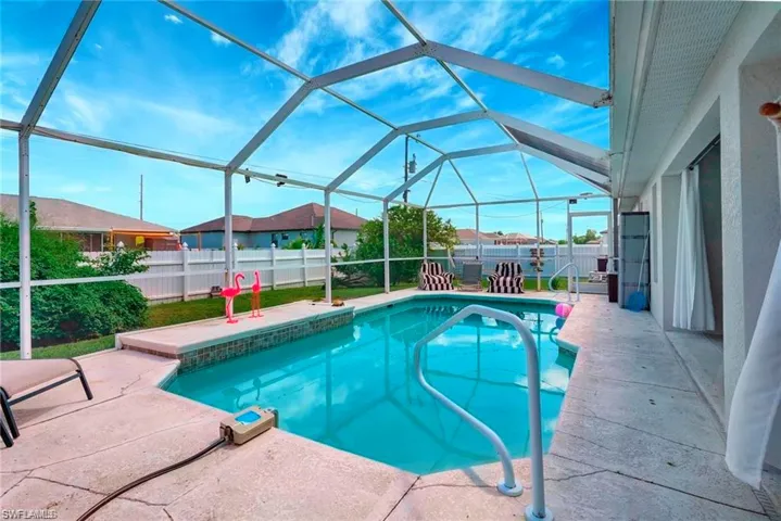 View of pool with a fenced backyard, patio surround, glass enclosure, and a sunroom