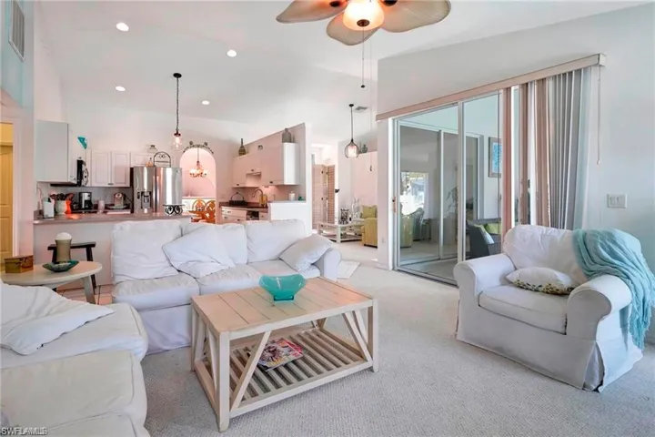 Carpeted living area featuring a ceiling fan, recessed lighting, and vaulted ceiling
