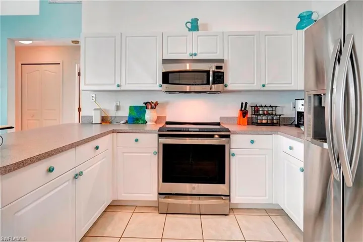 Kitchen featuring stainless steel appliances, white cabinets, light countertops, and light tile patterned floors