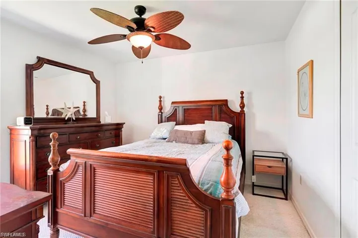 Carpeted bedroom featuring ceiling fan and baseboards