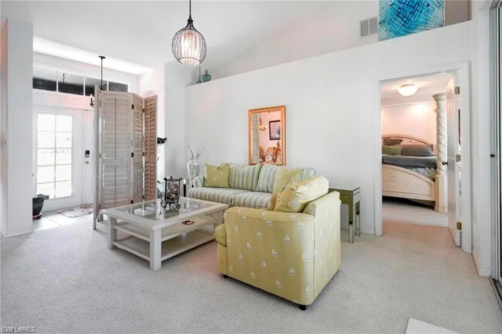 Carpeted living area featuring lofted ceiling and baseboards