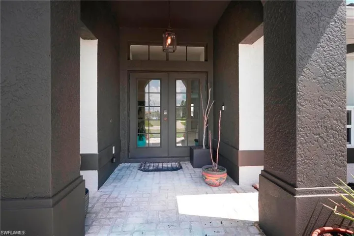 Doorway to property with french doors, stucco siding, and covered porch