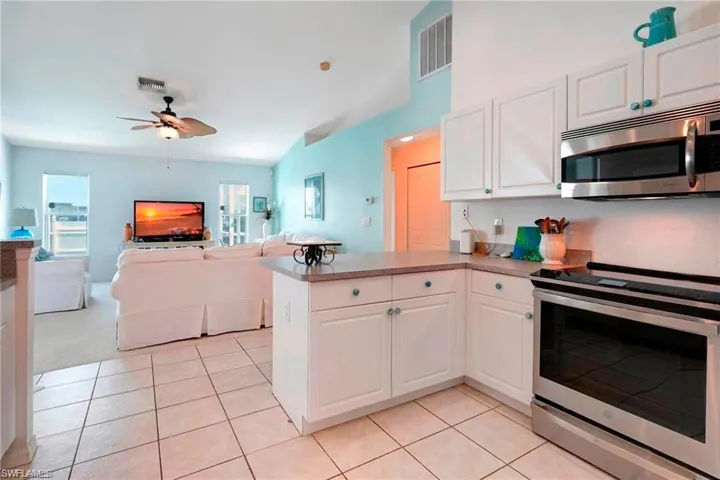 Kitchen with stainless steel appliances, a peninsula, white cabinetry, open floor plan, and light tile patterned floors