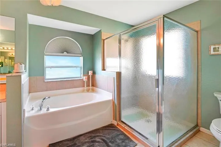 Full bathroom featuring a stall shower, a garden tub, tile patterned flooring, and vanity