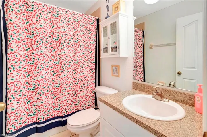 Full bathroom with vanity, a shower with curtain, and light tile patterned floors