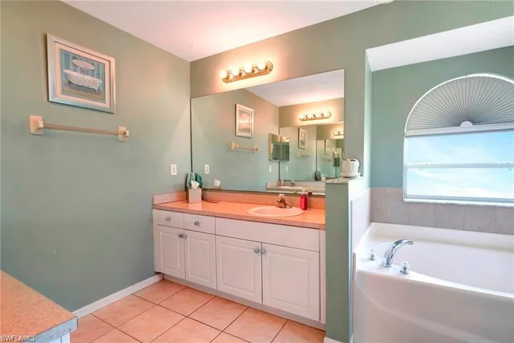 Bathroom with a bath, vanity, and light tile patterned floors