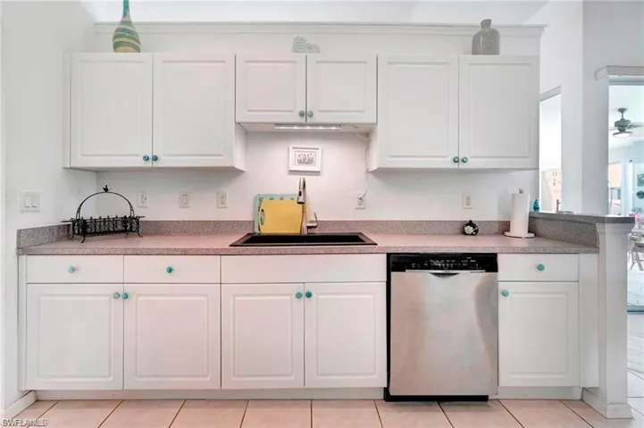 Kitchen with white cabinetry, dishwasher, light countertops, and light tile patterned floors