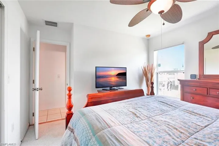 Bedroom with ensuite bathroom, a ceiling fan, and carpet